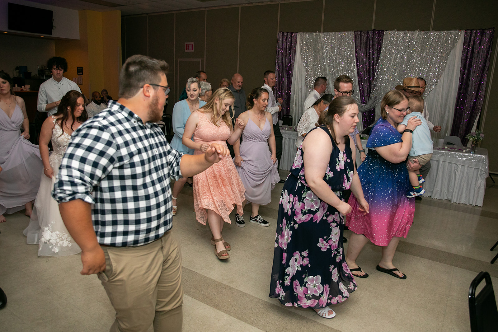 Wedding guests filling the dance floor beneath a sparkling sequin backdrop