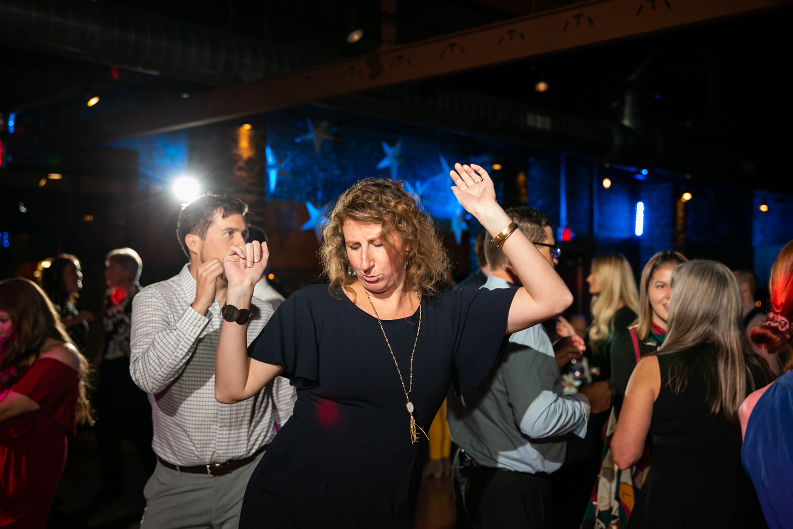 A guest dancing under warm party lights in a dim event venue