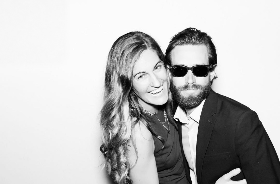 A couple posing close together in a black-and-white photo booth portrait